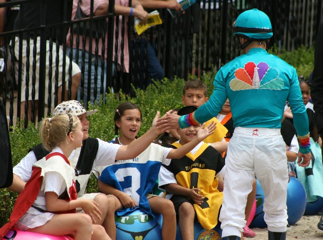 Del Mar Camp kids waiting to start the hippty hop race on the track get high-fived from a jockey. 